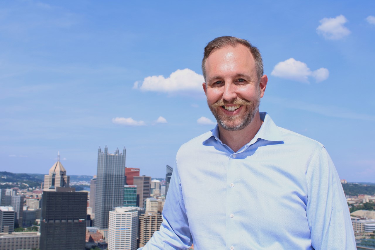 Pittsburgh property management services are provided by iTrip Pittsburgh, owned by Jeremiah Dodrill. Jeremiah is pictured here smiling in a button-up shirt with the Pittsburgh skyline in the background.